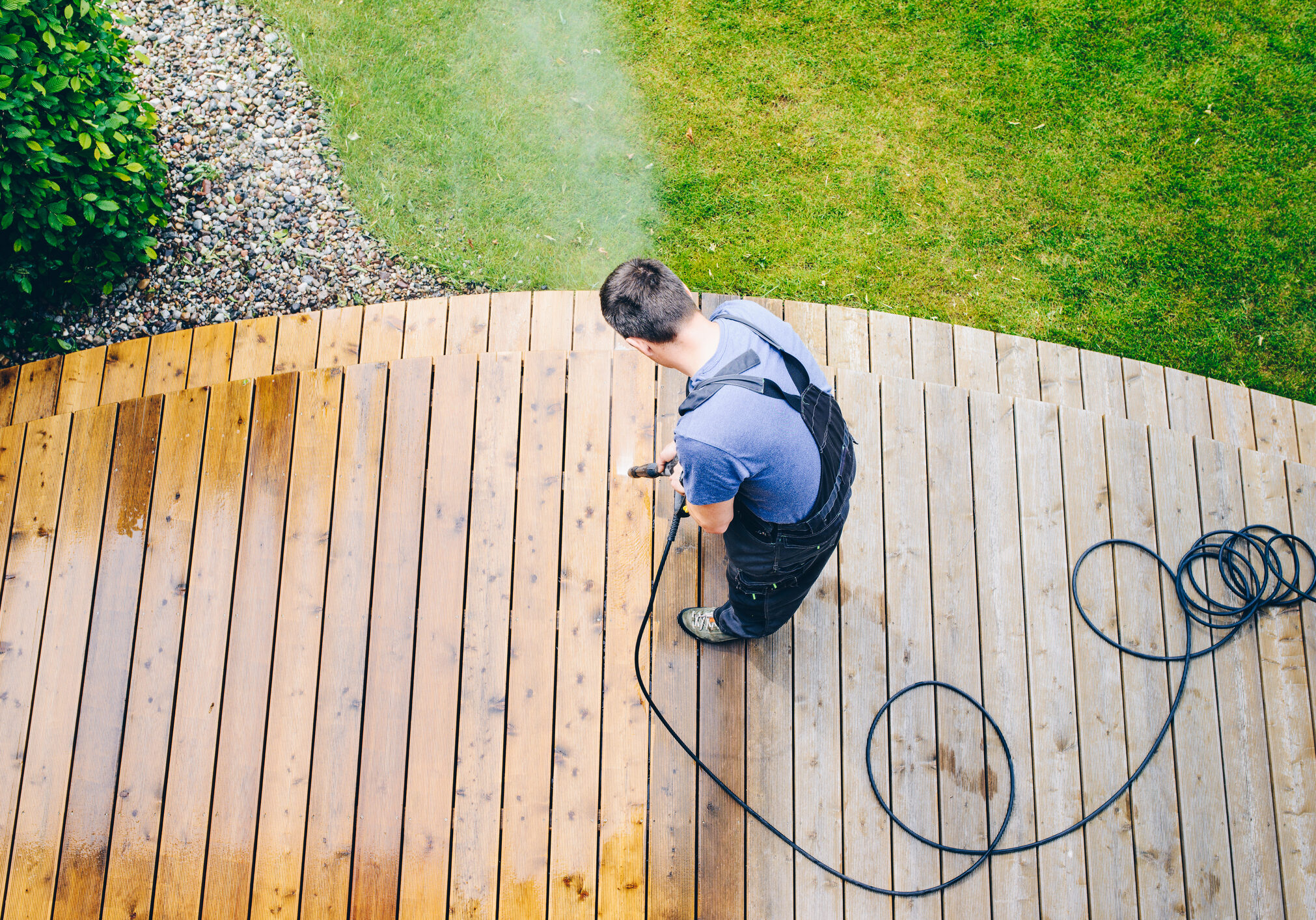 cleaning terrace with a power washer - high water pressure cleaner on wooden terrace surface
