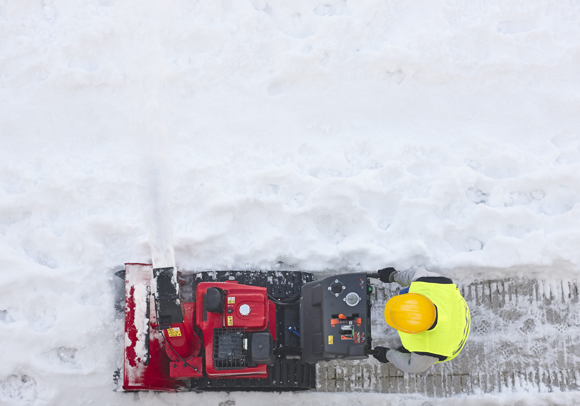 Worker cleaning snow on the sidewalk with a snowblower. Maintenance